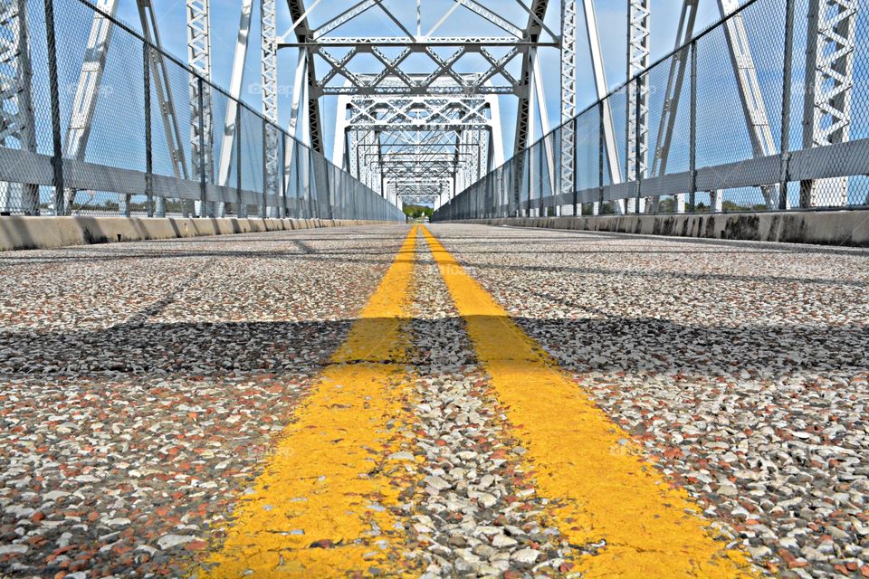 Symmetry - A symmetrical ground level view of yellow stripes on the roadway on a bridge. Symmetry is important in bridge design because the entire length of the bridge must be able to bear heavy weights