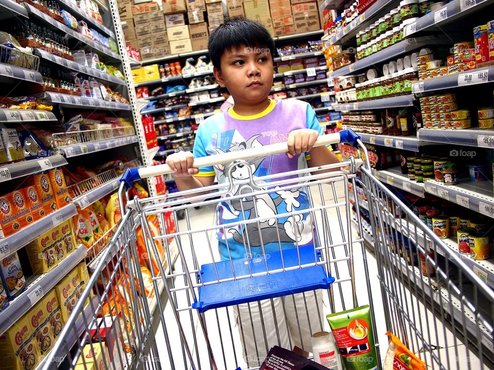 young boy pushing a grocery cart inside a grocery store