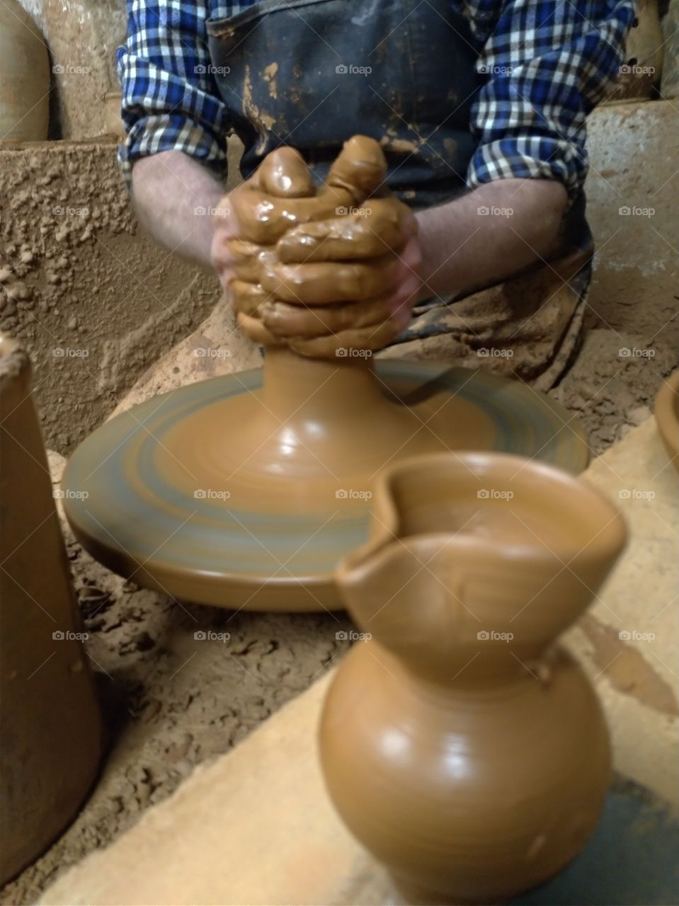 Manos de artesano haciwndo una pieza de barro en el torno