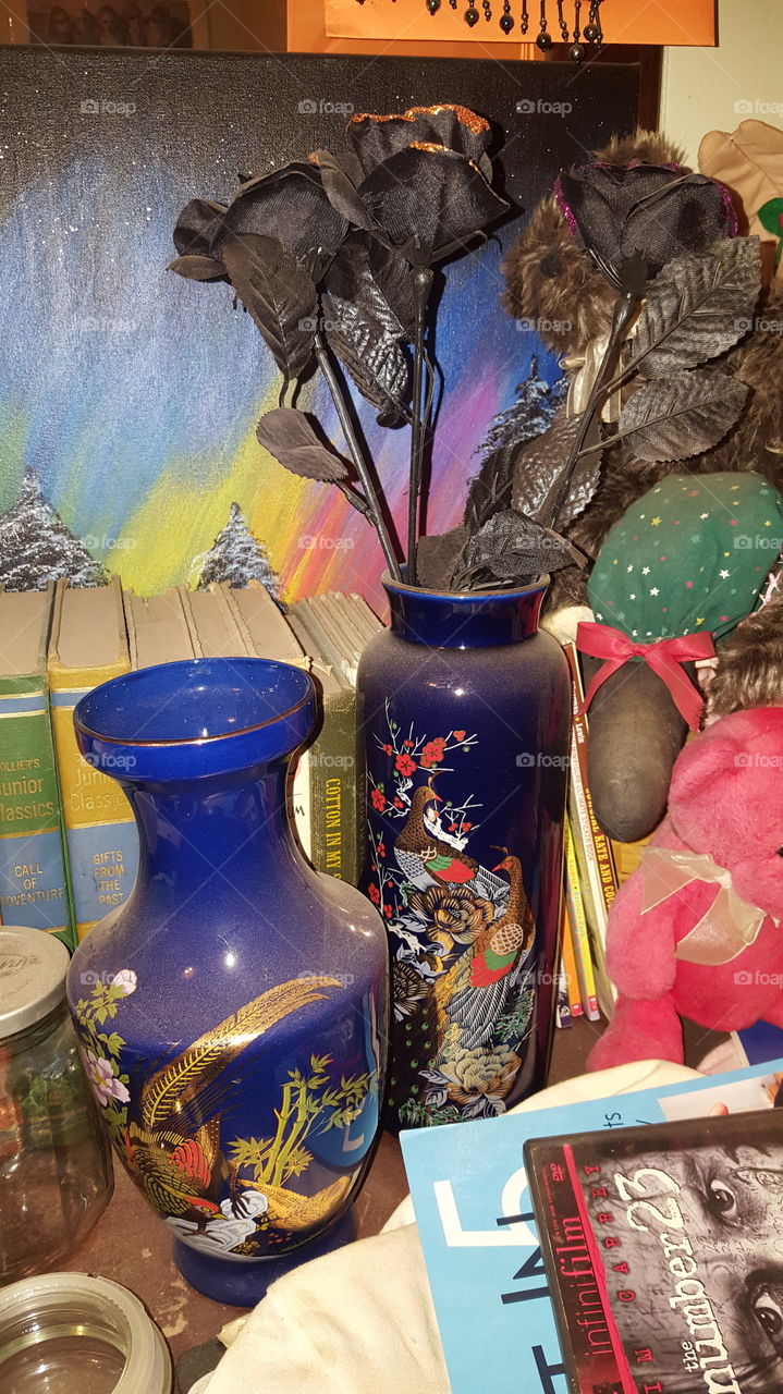 Old vases in blue color with some kind of Asian art painted on it. Black with orange sparkle Halloween flowers inside the vase. With an art painting that my mom made using blues, yellows, oranges and pinks.