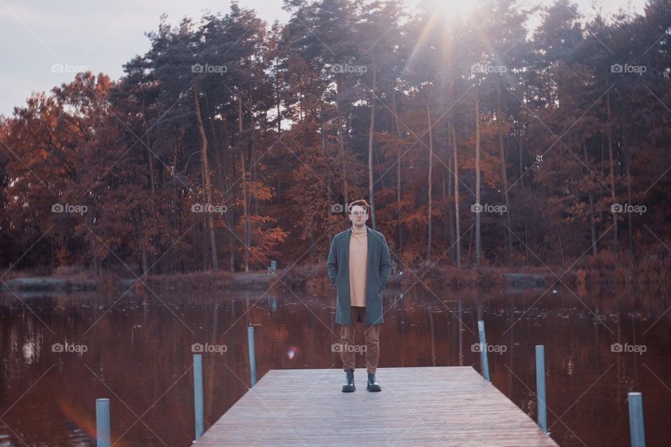 A man in a raincoat stands on the bridge