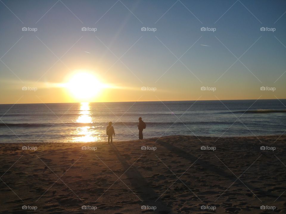 Enjoying the sunset. Father and son admiring coastal sunset