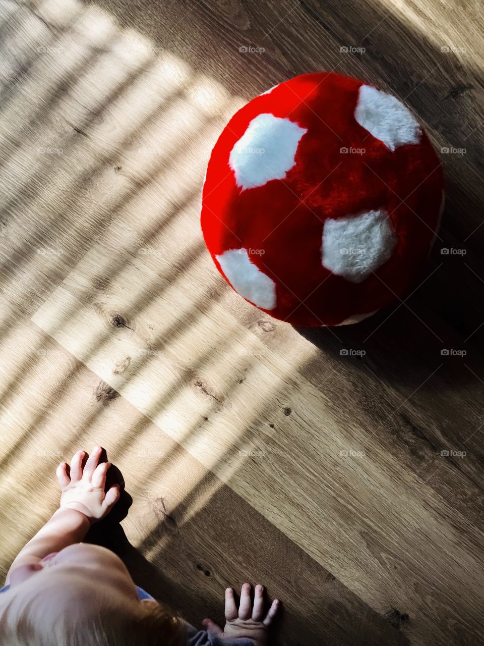 Little baby and fluffy football ball on the floor, top view