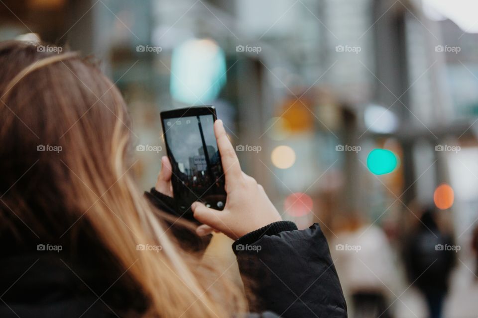 A young woman taking city pictures on her phone