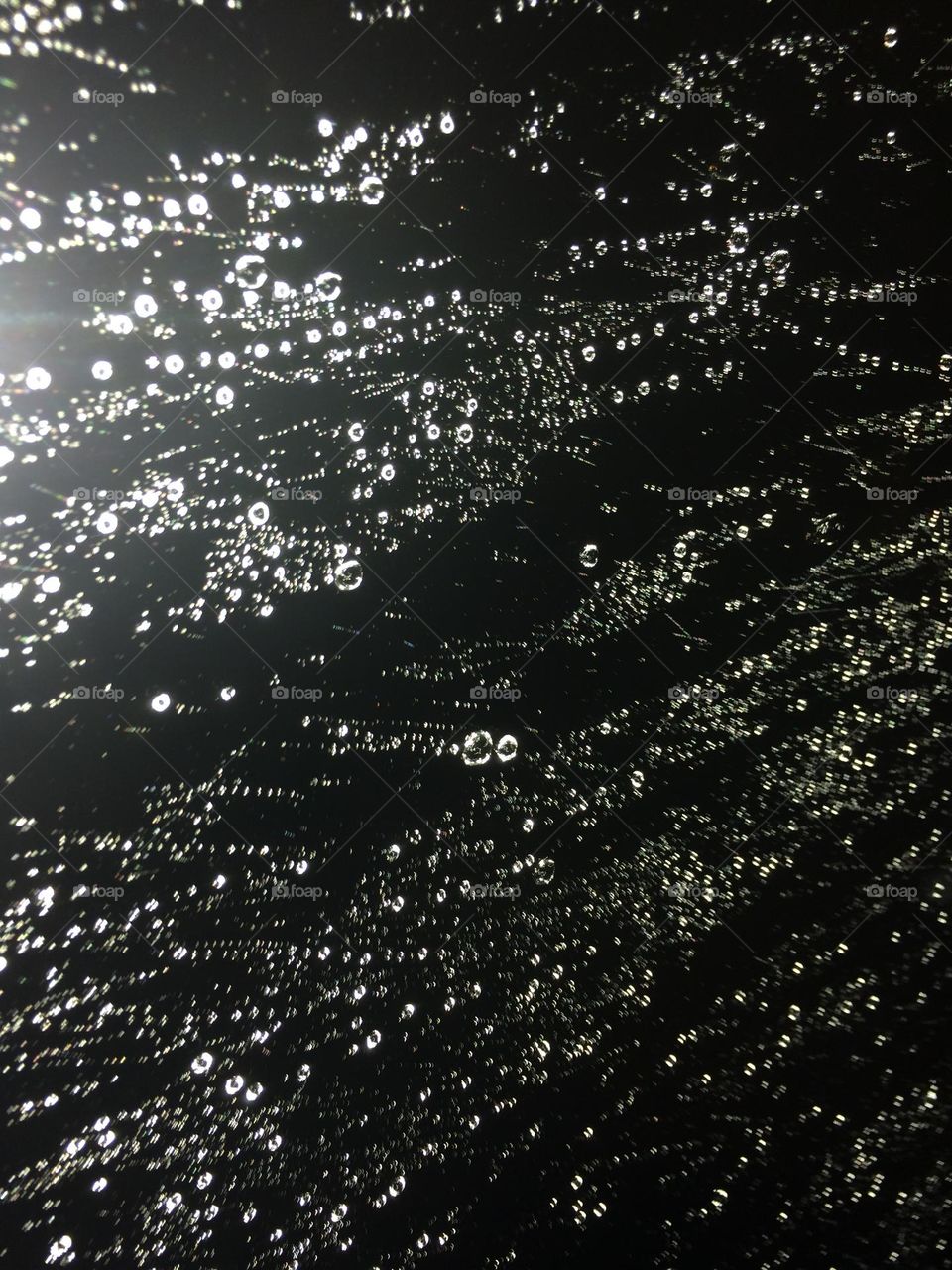 Driving through the storm in the dark, capturing small raindrops on the window at night