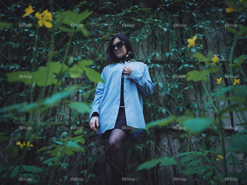 Portrait of beautiful woman wearing in retro style standing in the park near ivy wall 