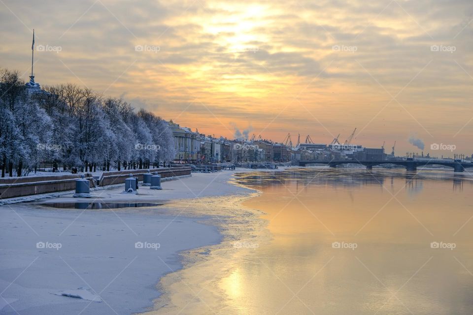 Sunset on the snowy city embankment