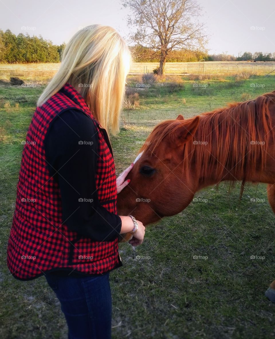 A woman petting a horse in the fall