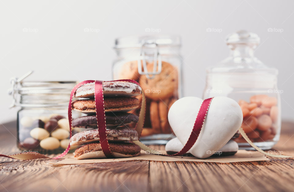 Gingerbread cookies, candies, cakes, sweets in jars on wooden table