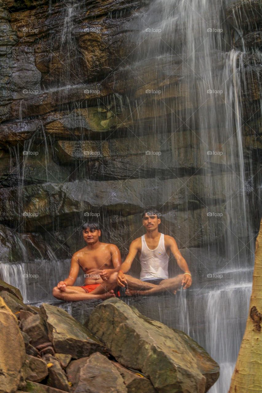 People in yoga pose under waterfall