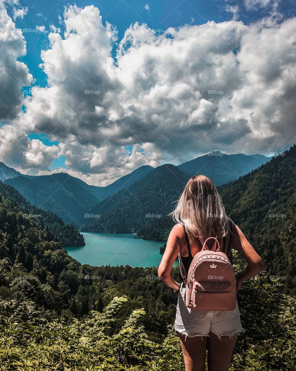 girl admires the views of a mountain lake