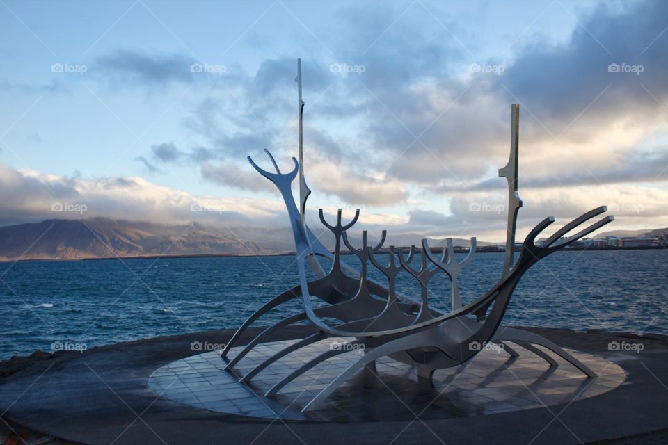 Sculpture of The Sun Voyager in Reykjavik with a pretty blue sky on an early morning and some clouds and the ocean next to it.