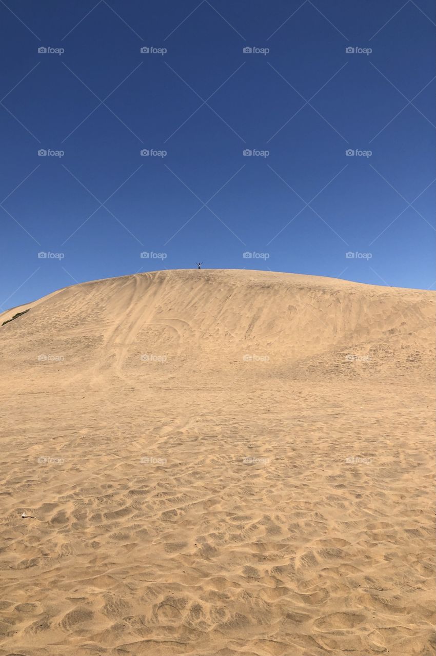 Alone on a dune in a blue sky