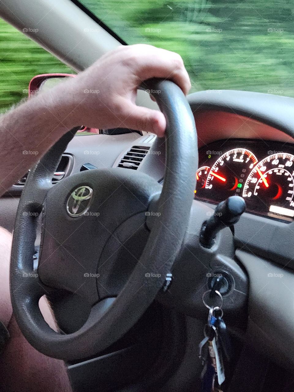 close-up of man's hand on the wheel driving and a view of the lit up dashboard.