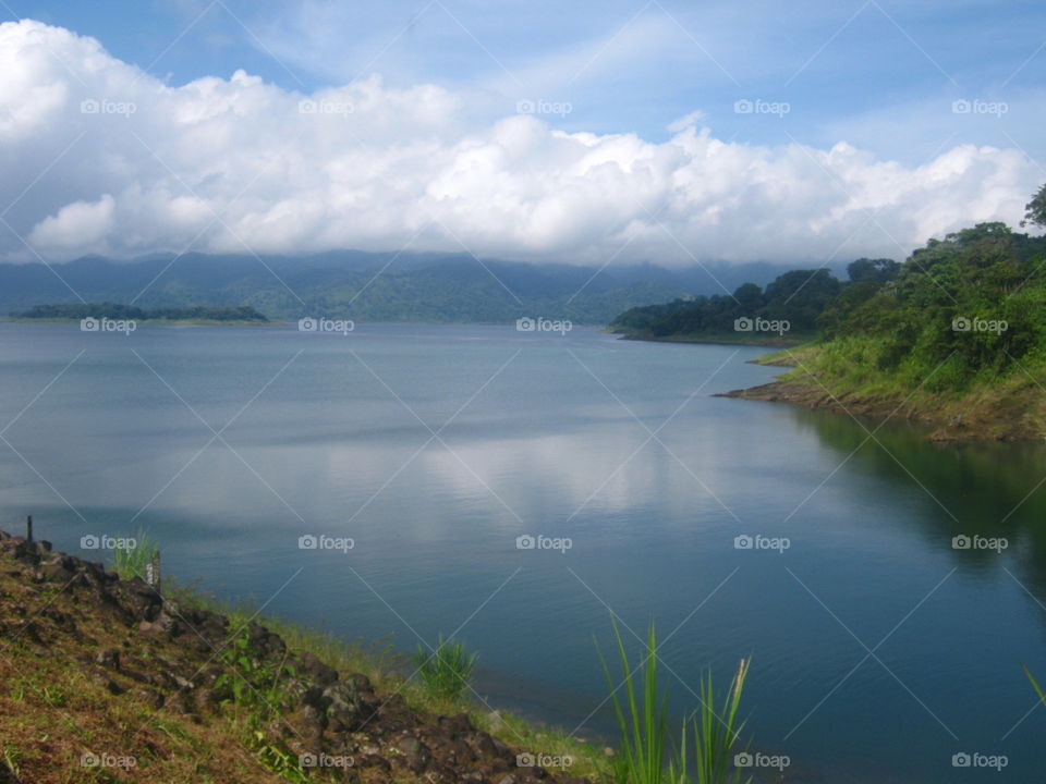 The clouds reflect in the clear water of Lake Arenal next to the volcano in Costa Rica
