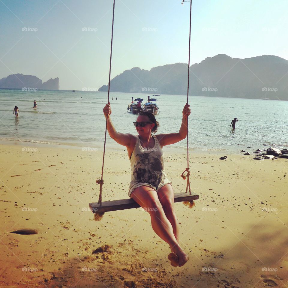 Woman sitting on swing at beach