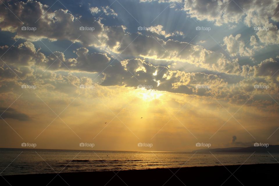 beautiful sea sunset in the clouds. rays of the sun through the clouds. summer. sea. beauty of nature
