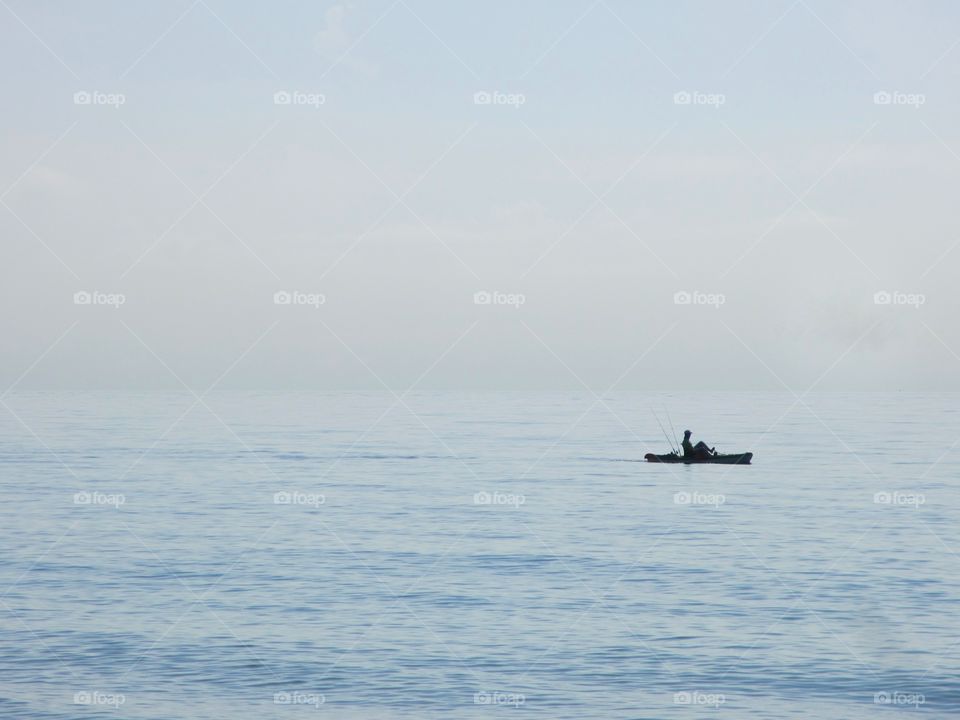 Solitary ocean kayak on calm sea water on a misty morning