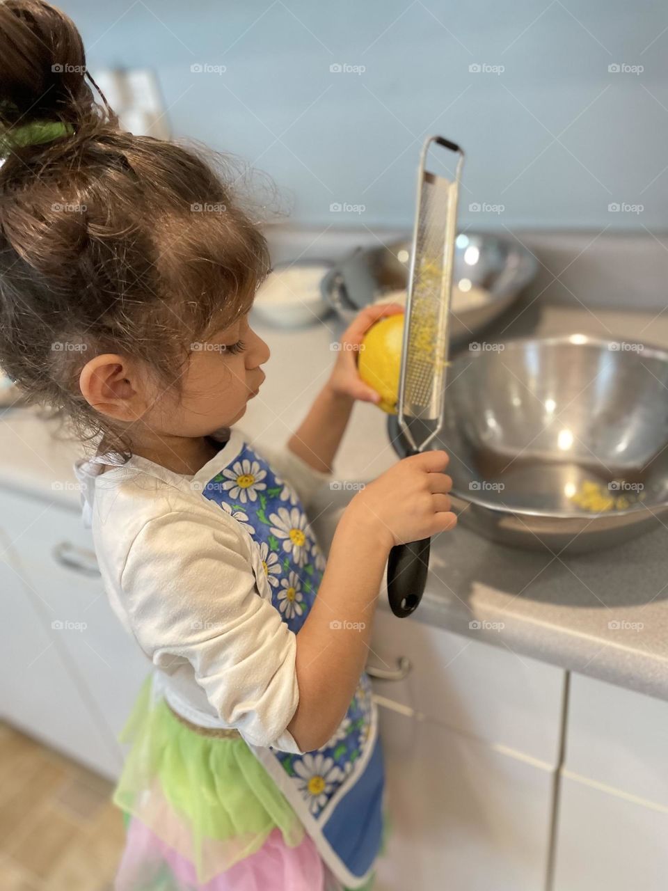 Toddler girl zests lemon for recipe, little hands helping in the kitchen, making cookies with mommy, baking with mommy, toddlers helping in the kitchen 