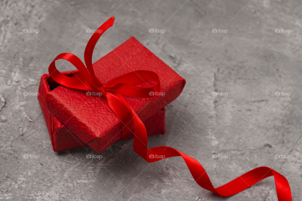 red gift box with ribbon on concrete background.  Christmas gifts concept