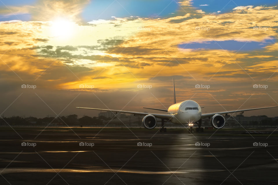 A Boeing plane is taxiing before taking off at Manila Airport (Philippines) in the early morning, illuminating its path with headlights, against the backdrop of a very beautiful cloudy sky at sunrise in the early summer morning.
