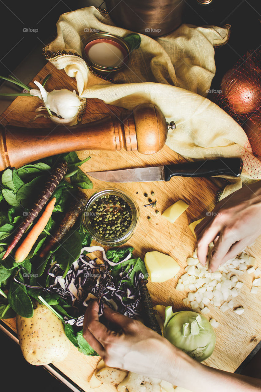 Cooking and preparing fresh vegetables with spinach, cabbage, carrots, kohlrabi, green peppercorn, chopped onion and sliced potatoes flat lay on wood table
