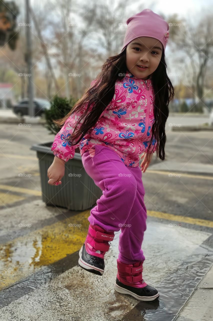 Beautiful girl in the spring jumping through the puddles
