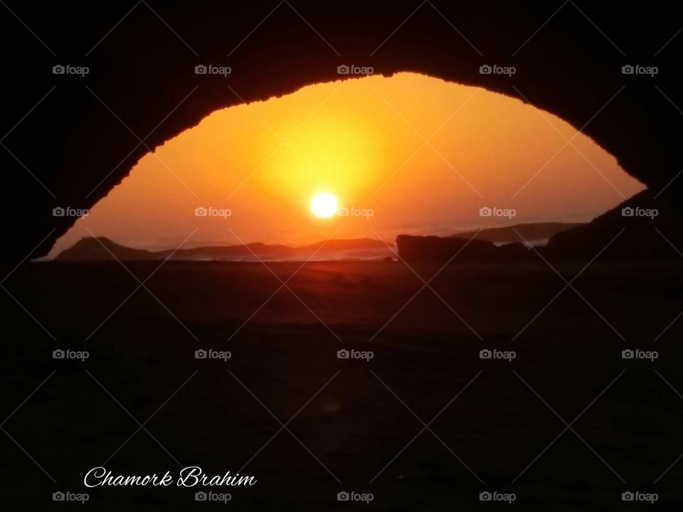 Sunset under an arch in Elghzira beach,Ifni,Morocco