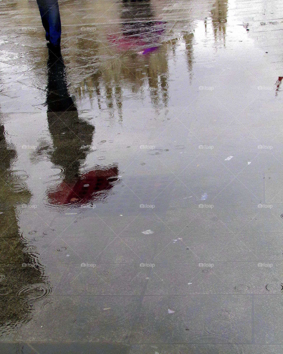 colored umbrellas reflecting into puddle
