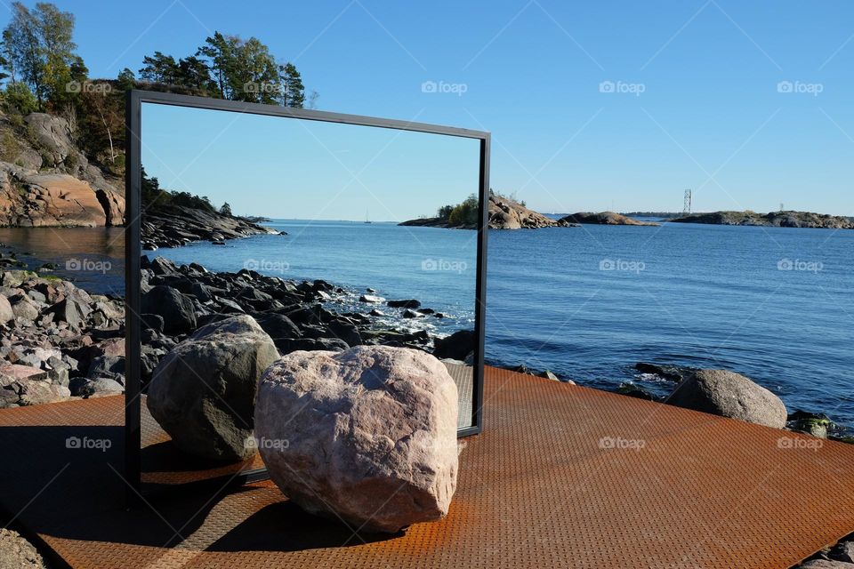 Reflection in the mirror: open air museum installation two big rock on both sides of the mirror on the Vallisaari island