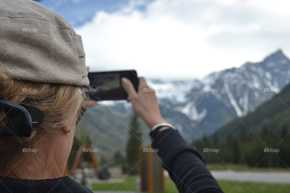 Woman capturing a photo of the snowy Canadian Rocky Mountains 