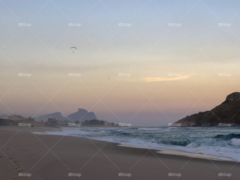 Beautiful sunset on a beach in Rio de Janeiro With mountains and a parasail 