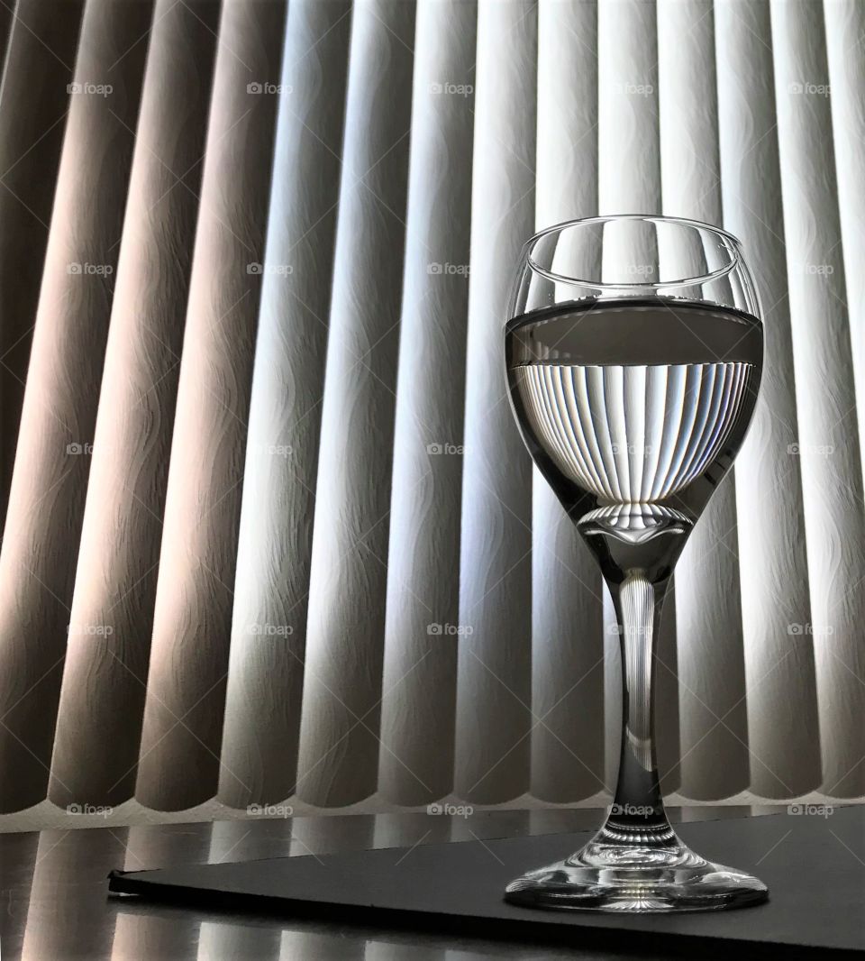 Composition, wine glass with blinds reflecting in drink