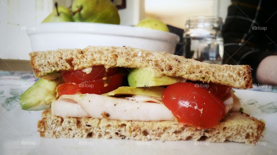 Turkey avocado tomato dijon mustard on whole grain wheat sandwich is my favorite sandwich pears in the background with a glass of water