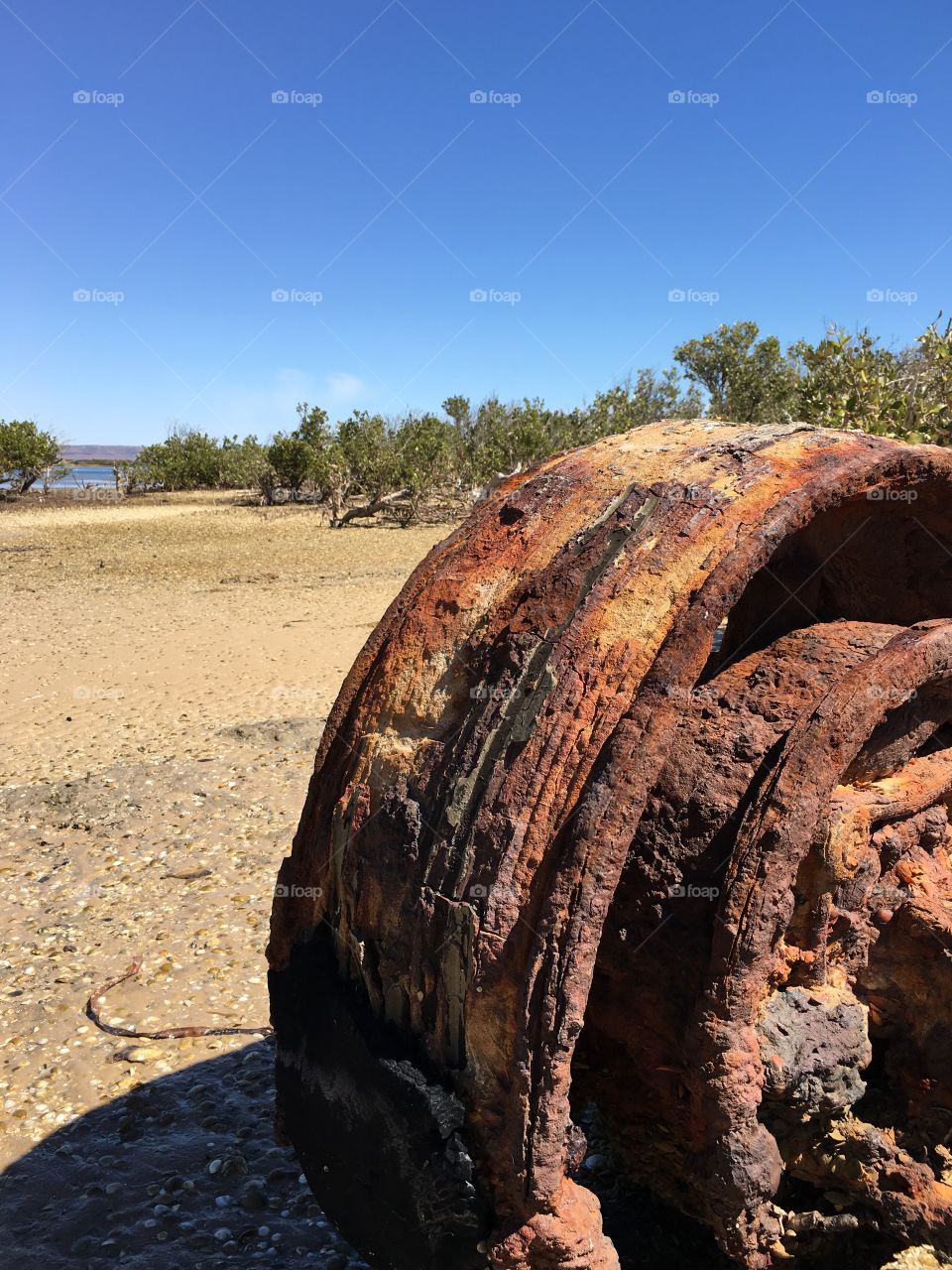 Rusted wheel and axel washed ashore at low tide in Australia 