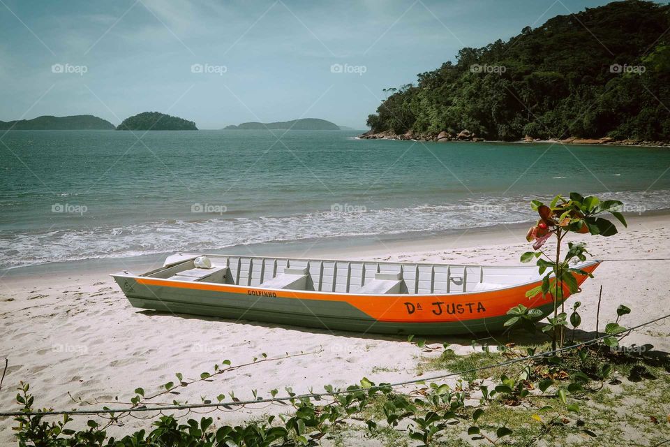 Small orange and green Canoe at Praia da Justa, Ubatuba, Brasil. Beautiful Sunny Day at the Beach