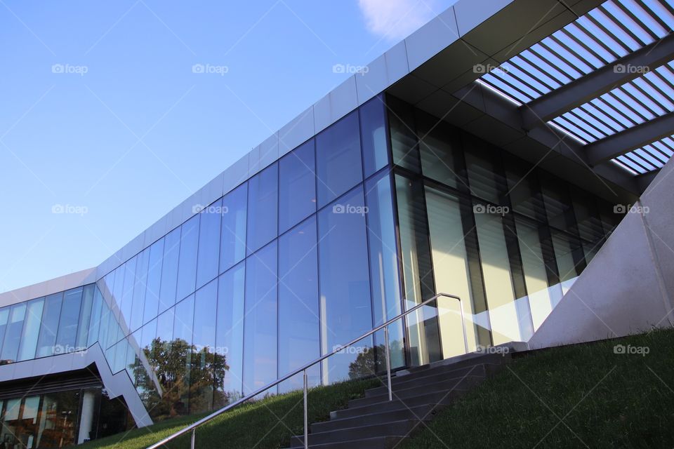 Glass building with rectangle windows and arbor stands beautifully beneath blue skies