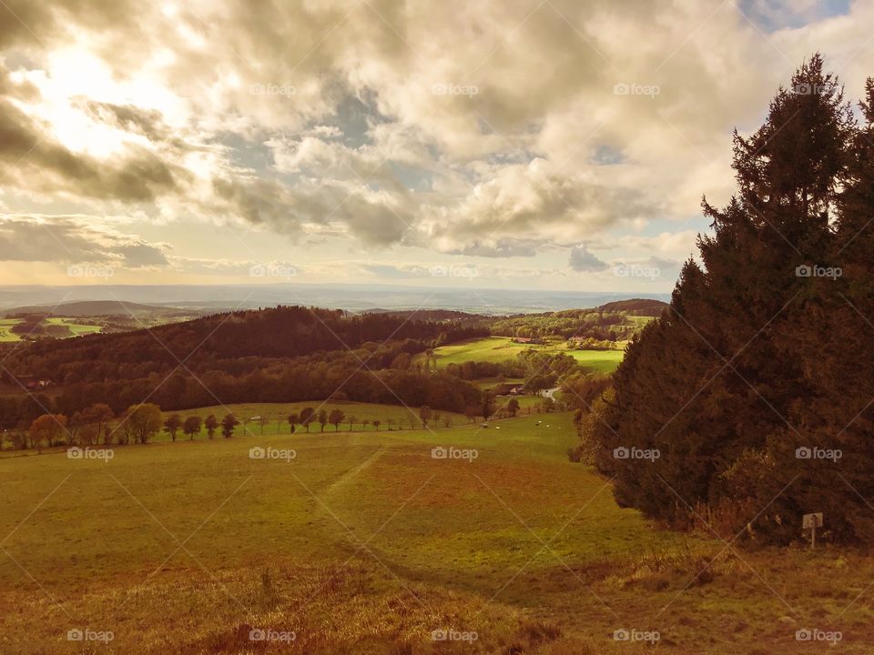 Natural scenery in the autumn ,the grasslands and trees had changed colors.The sky has a lot of gray clouds, It is not sunny, the light only shines in a few places. The weather is cool and I am on a hiking trip