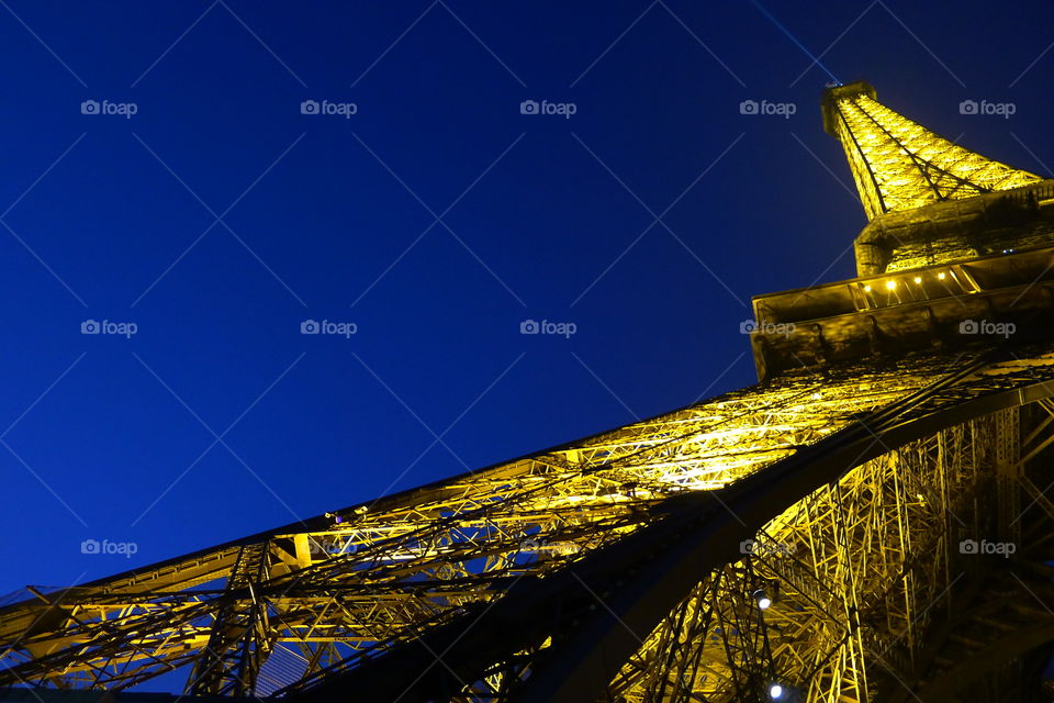The Eiffel tower, from below, illuminated against a clear night sky