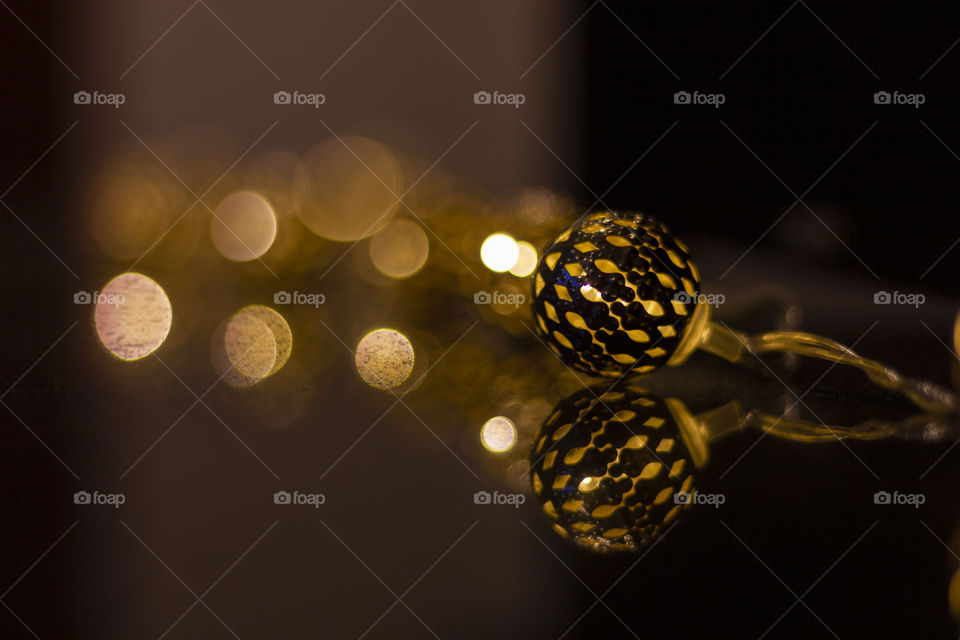 A closeup portrait of an ornament with a light in it. perfect for decorating your house and setting/creating a cosy warm mood. in the background there are lights transformed into bokeh balls.