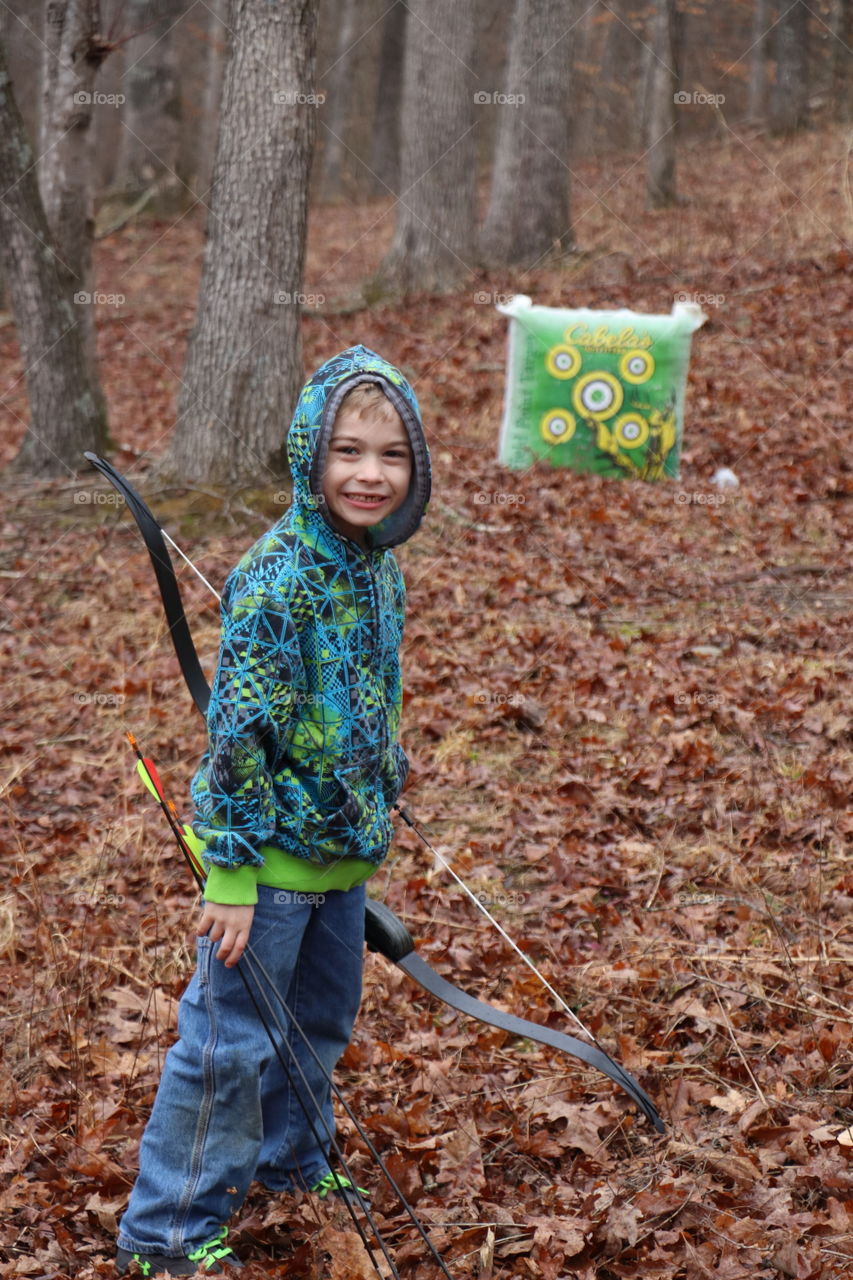 Cute boy holding bow and arrow in forest