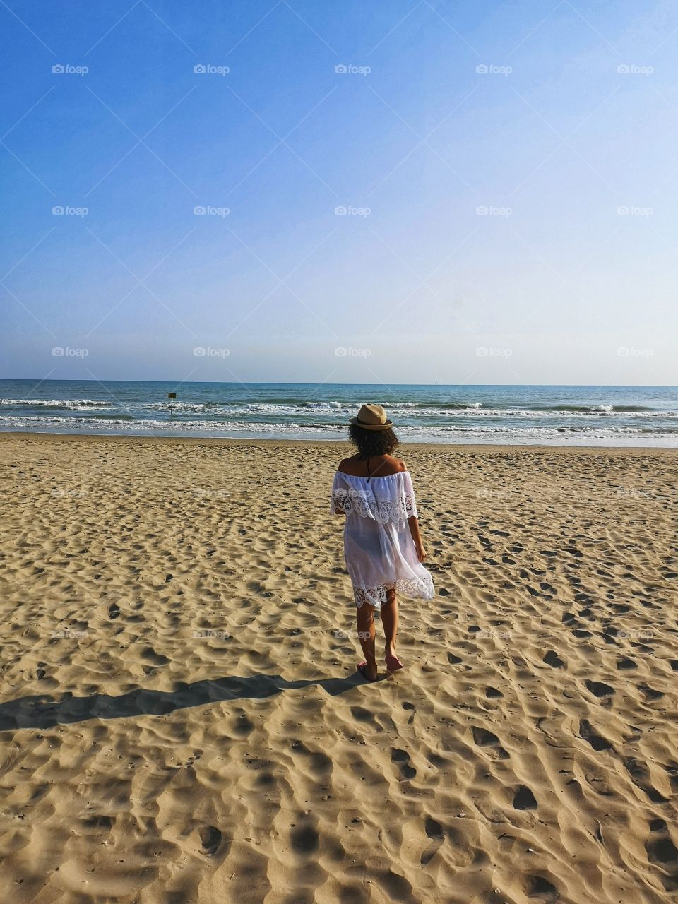 Lonely woman, from behind, looks at the sea and meditates