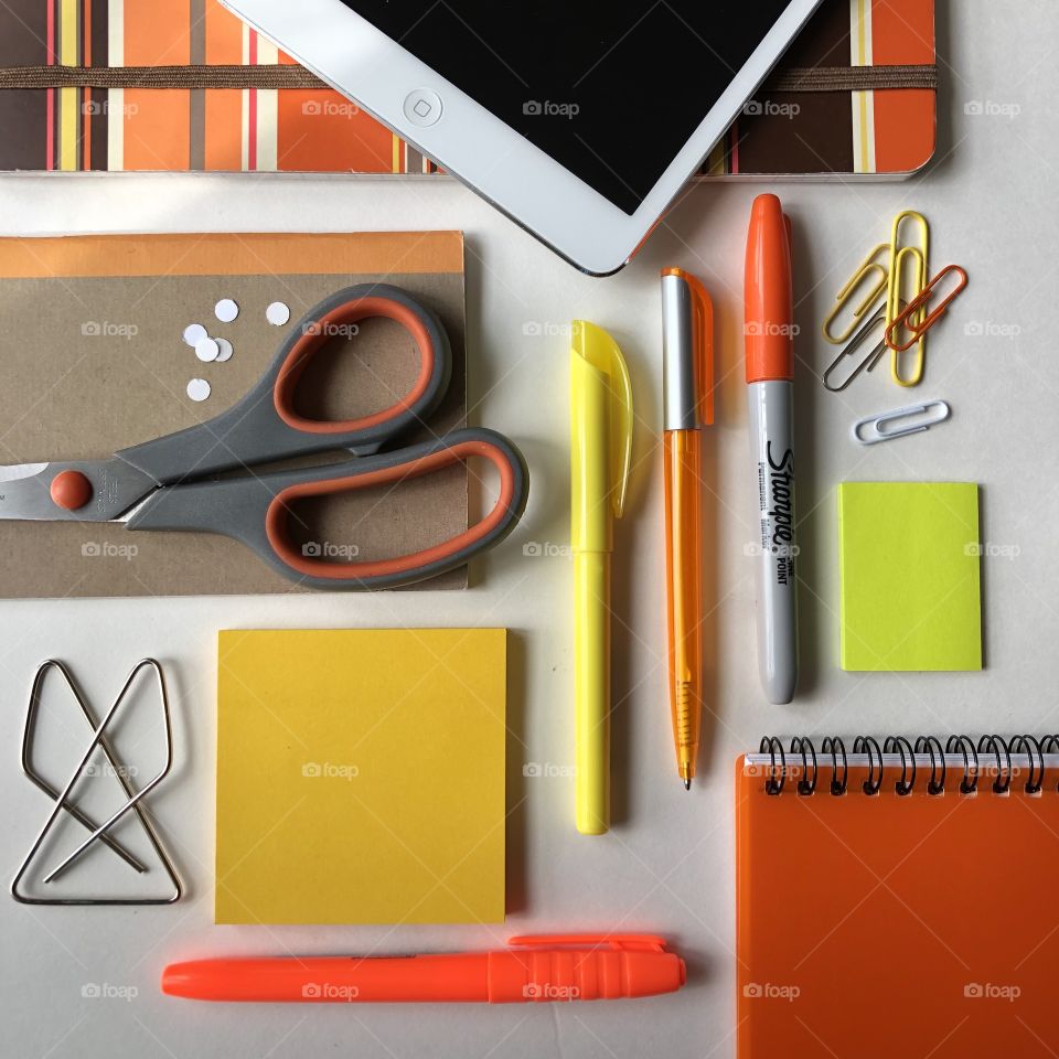 Orange and yellow themed flat lay out of office supplies, technology and desktop