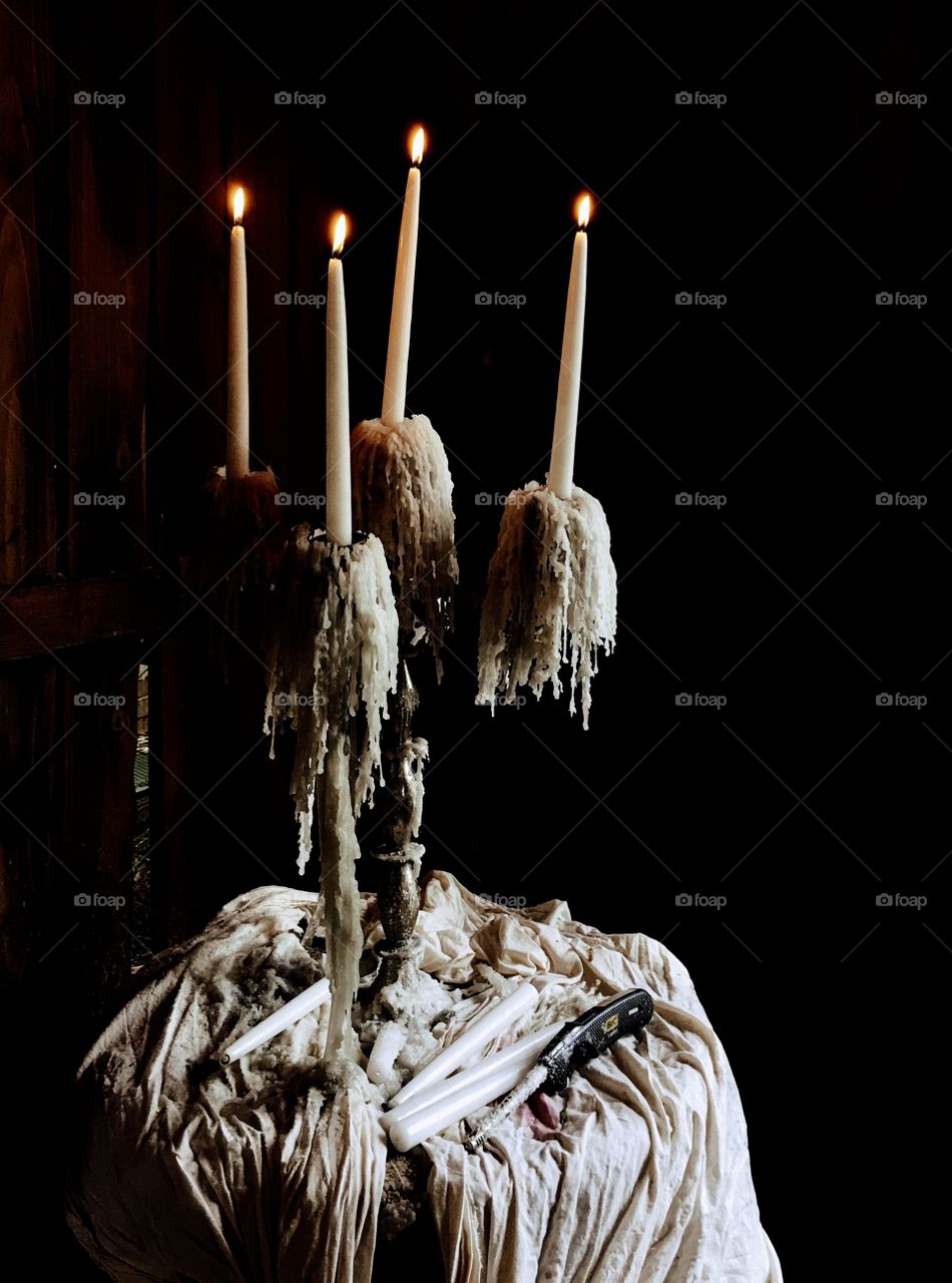 Four candle candelabra lit in darkness with light from the side shining on it. 