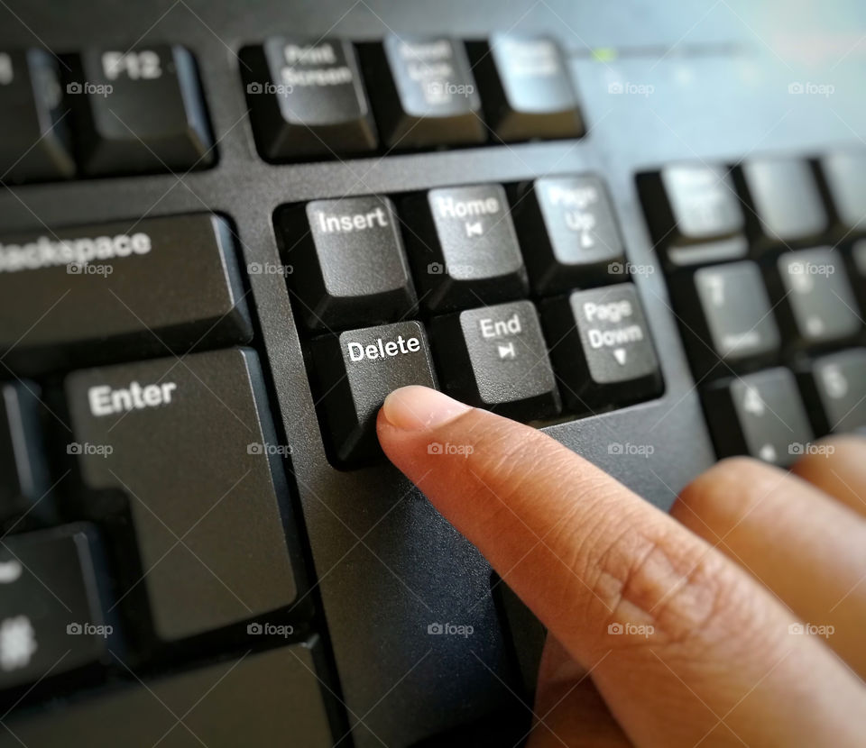 Finger pressing Delete button on computer keyboard