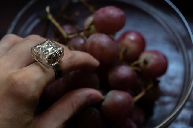 A hand with a sparkling ring takes grapes
