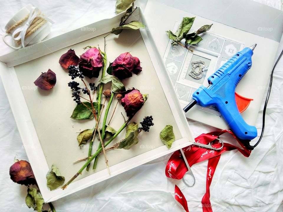 the process of making a painting from dry roses using hot melt glue