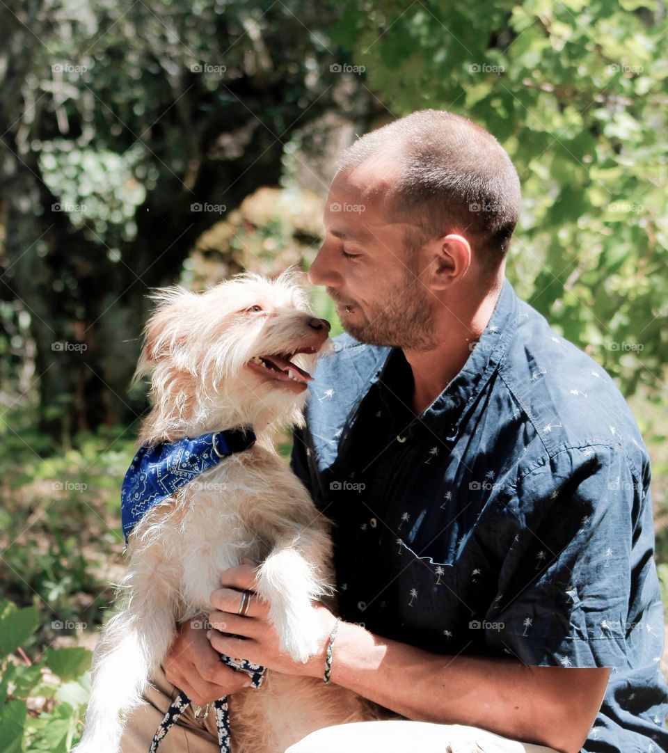 A man and his dog look at each lovingly surrounded by greenery on a bright sunny day