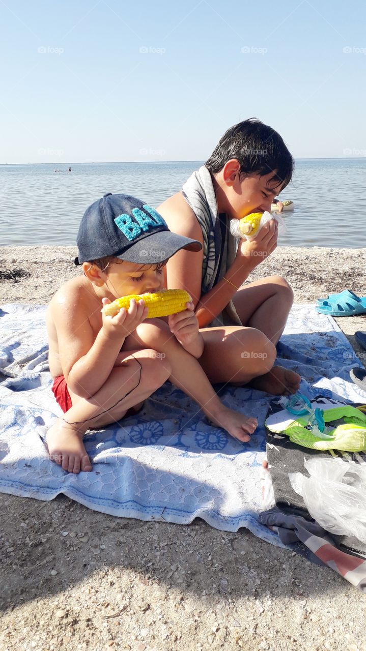 two boys eating a corn