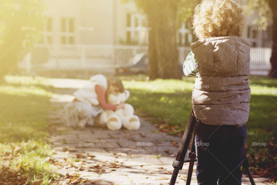 kids playing with camera. little boy photographing little girl with a camera on stand